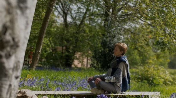 Woman meditating in a field of bluebells, UK.