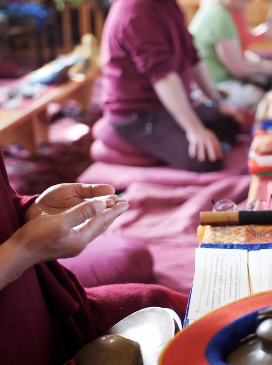 Tibetan Buddhist monk showing hand mudra during dharma teachings.