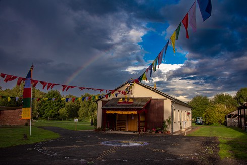Buddhism meditation hall for worship, in the dark, with prayer flags and a rainbow.