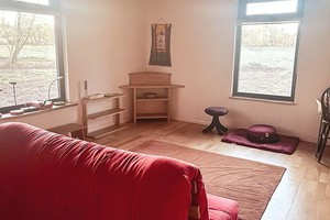 Room with sofa and big window for meditation at solitary retreat hut.